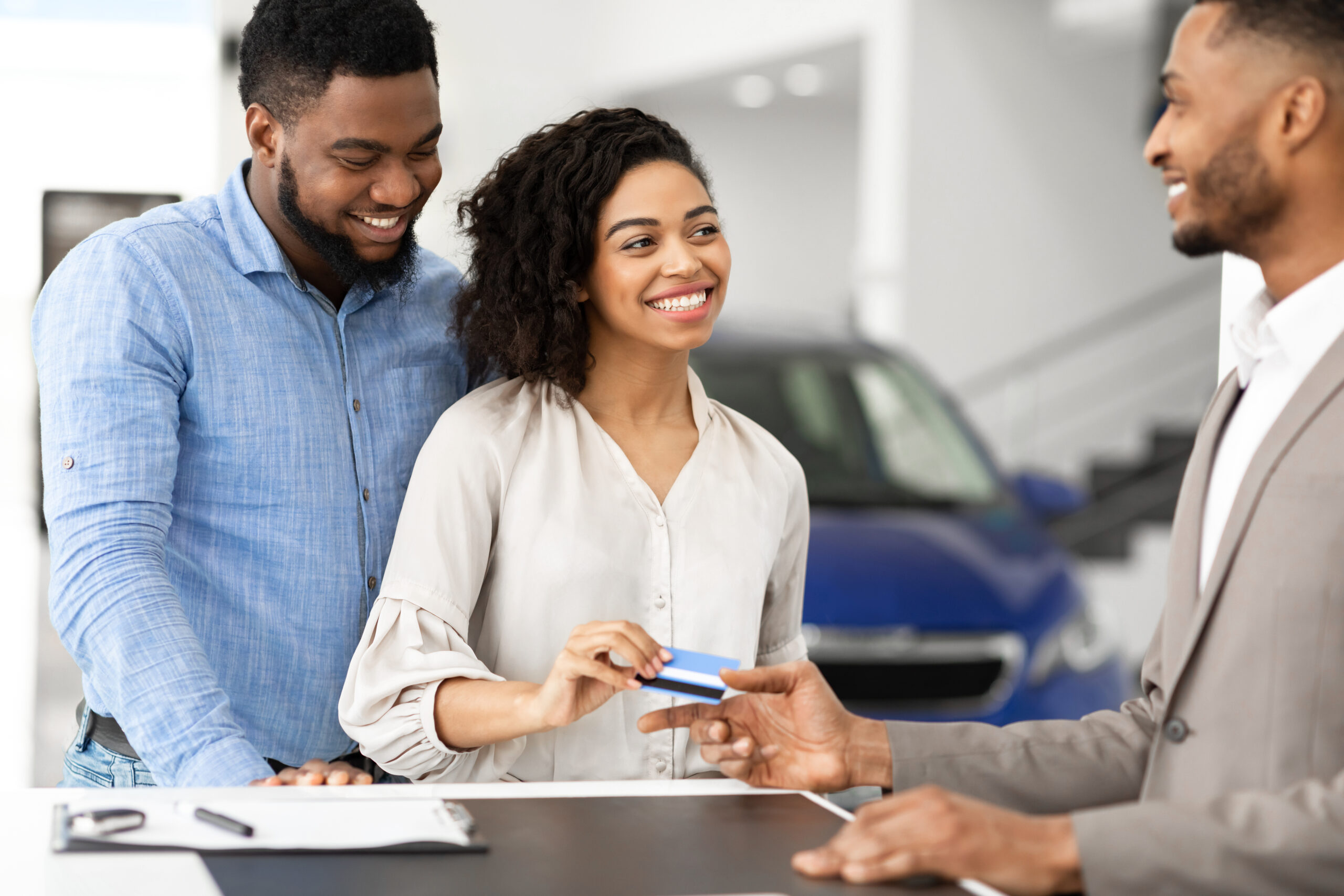 Buying,Car.,African,American,Spouses,Giving,Credit,Card,To,Salesman